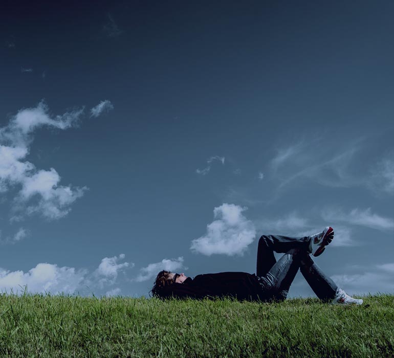 homme allongé dans l'herbe en train de réfléchir